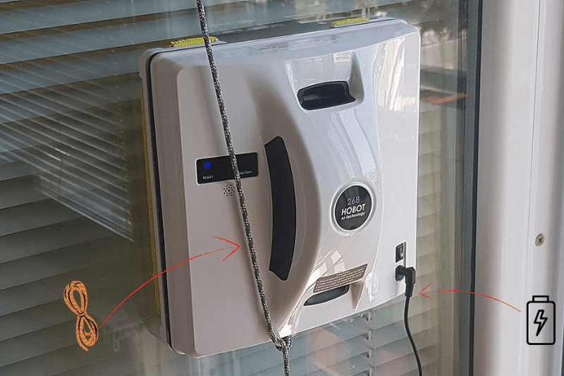 Man sieht den Hobot 268 ein Fenster putzen, während das Gerät gleichzeitig am Sicherungsseil befestigt ist.